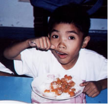 Boy eating rice & meat meal from a plate